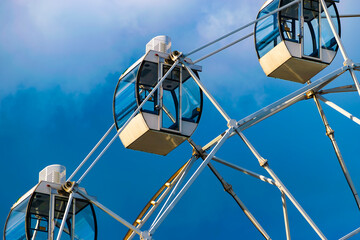 Ferris wheel on the background of a blue sky with clouds. Close-up. Part of the wheel.