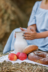 Red apples, fresh homemade bread on a white lace napkin in the hands of a woman in a blue dress. Elements of Russian national cuisine. Photo of food in the autumn.
