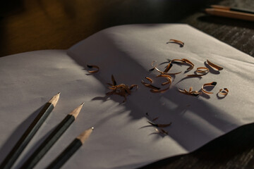 Wooden pencils with sharpening, shavings on white paper