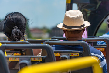 Back view of tourists, man with a hut and a women rides on a double decker bus for sightseeing, Buenos Aires