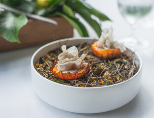 detail of a haute cuisine dish made with two small mushroom tarts on a base of dried herbs.