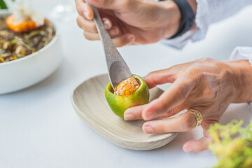 a person tastes a haute cuisine dish of lemon, foie gras and honey with a wooden spoon.