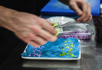 a chef preparing small flowers to decorate the dishes. motion blur on the hands. haute cuisine...