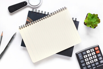 open notepad on a white background. with place for text. near a calculator, magnifying glass and plants in a pot