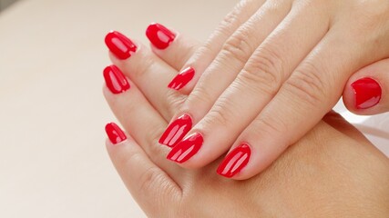 Female hands with fashionable manicure of red color . Woman shows her new red manicured nails, closeup. Beauty of nails. Classic red manicure.