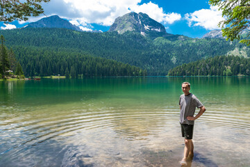 Man tourist near glacial Black Lake with Meded Peak. Tourist attraction of Durmitor National Park.
