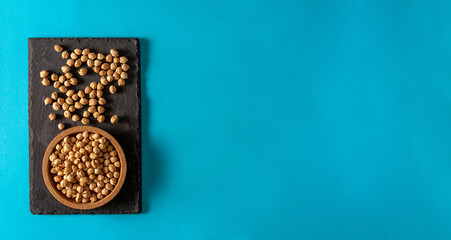 Chickpeas on slate surface and cork bowl on blue background. Flat lay. Copy space.