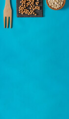 Chickpeas and beans in slate and cork containers on blue background. Flat lay. Copy space.