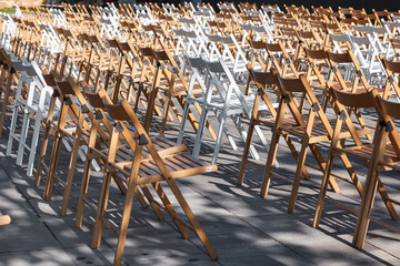 Folding chairs are arranged in the area for outdoor activities . Rows of empty folding wooden...