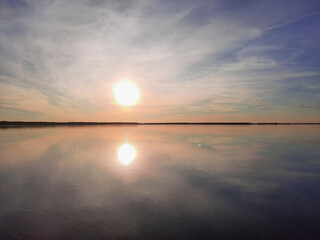 Fototapeta premium Shatsky Lakes. Ecotourism. Shatsk National Natural Park. Landscape of the setting sun on the lake. Blue skies and gentle water with sun tints. The mirror water of the lake reflects the sky.