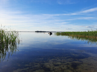 Shatsky Lakes. Ecotourism. Shatsk National Natural Park. Landscape of the setting sun on the lake. Blue skies and gentle water with sun tints. The mirror water of the lake reflects the sky.