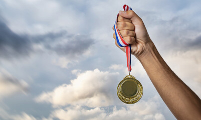 Plakat Medal gold in winner hand. First place award, sky background. Sport champion athlete victory concept