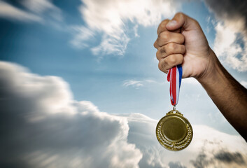Fototapeta na wymiar Medal gold in winner hand. First place award, sky background. Sport champion athlete victory concept