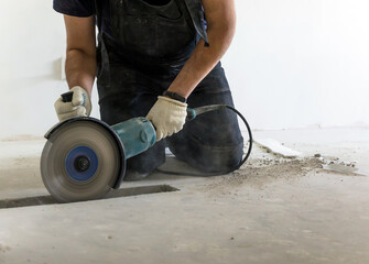 cutting concrete floor screed bolarka man in construction combenizon and work gloves. power tools. floor repair. dust and sparks
