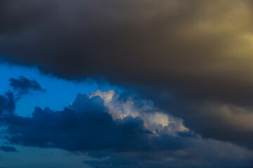 Naklejka na ściany i meble Large white and dark clouds against the blue sky background.