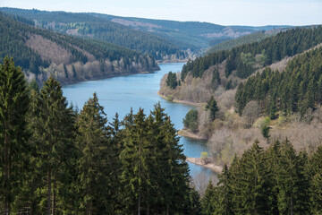 Blick auf eine Talsperre von oben mit Bergen und blauem Wasser
