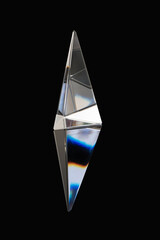dreieckiges Glasprisma mit Regenbogenfarben durch Sonnenlicht und Spiegelung im Untergrund