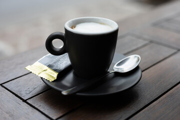 cup of coffee with cookie and spoon on wooden table 