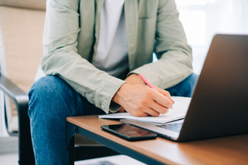 Caucasian man college student, studying with laptop distantly preparing for test exam writing essay doing homework at home, distantly education concept.