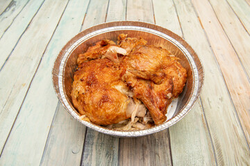 Traditional grilled chicken chopped in an aluminum container for take away