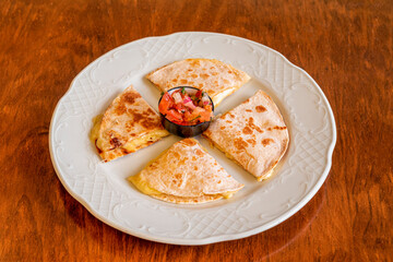 Mexican synchronized quesadillas with melted cheese and ham with pico de gallo on wooden table