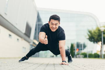 asian athlete performs sport pushing off the ground looks at the camera smiles and shows thumb up