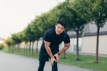 Asian man holding knee pain after running and fitness, severe leg pain