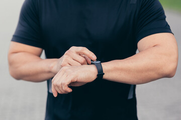 Close-up photo of a male athlete choosing a sports program on a fitness bracelet