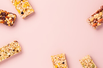 Granola bars. Healthy energy bars made of cereals, berries, nuts and fruits on a light pink...