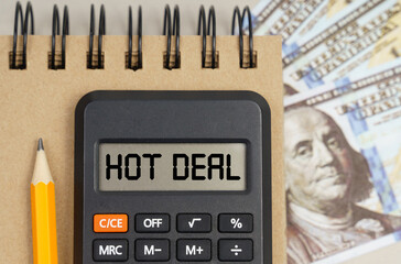 On the table there are dollars, a notebook and a calculator with the inscription - HOT DEAL