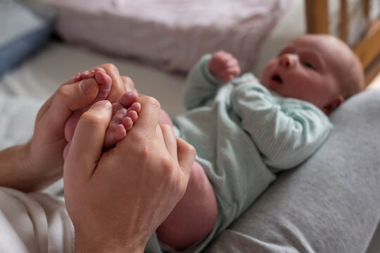Hands holding baby feet checking reflex of a newborn.