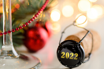 sparkling wine or champagne cork on table with christmas or new year 2022 blurred background and decorated fir-tree