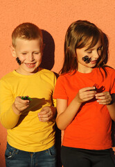  Cute children with a spiders on face holding a little pumpkins posing on orange background