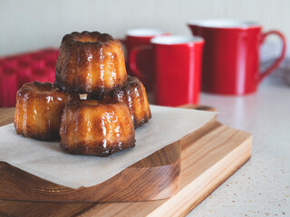 Caneles de Bordeaux on a wooden board. Famous French pastry. Coffee or tea cup accompaniment