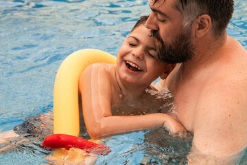 disabled boy with a float laughs as he plays and swims in a pool with his father