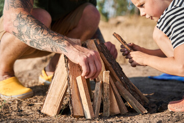 Inquisitive cheerful daughter communicates with her dad near the future campfire