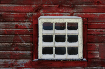 window of red barn with snow on the sill