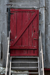 Fototapeta na wymiar red barn door at the top of wooden steps