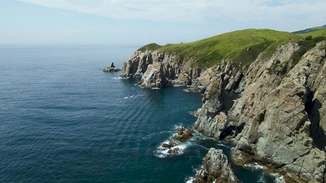 Aerial view, Rocks, Pacific Ocean, green grass on the mountains , bay