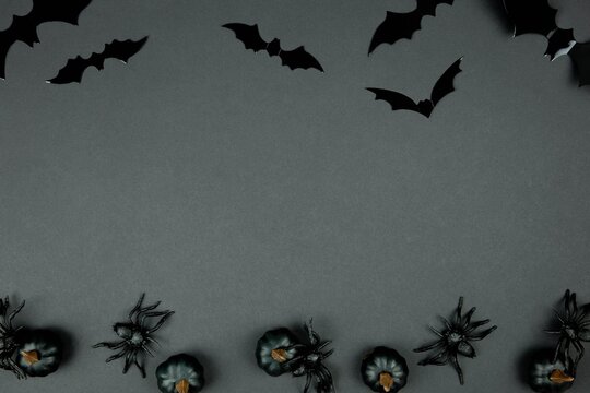 Happy halloween flat lay composition with black pumpkins, spiders and bats on dark background. Holiday concept. Top view. Copy space.