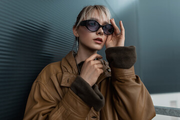 Fashion portrait of a beautiful young woman in a vintage brown leather jacket with stylish...