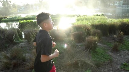14 year old boy jogs around a small lake in Los Angeles. Los Angeles skyline can be seen in the distance.