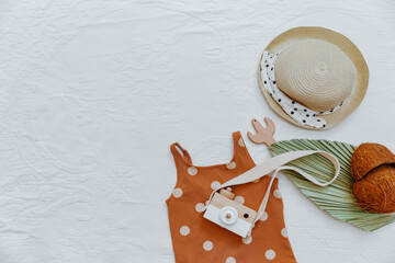 Set of baby summer accessories. Swimsuit for girl, kids toys and bib on white background. Top view, flat lay. Child holiday concept