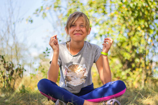 Defocus caucasian preteen girl practicing yoga in park, forest, outdoor, outside. Meditation, concentration, mantra. Wellness lifestyle. Portrait of smiling yoga girl. Nature background. Out of focus