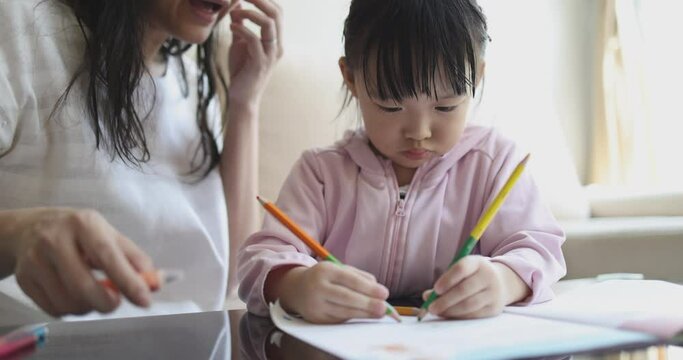 4K Video slow motion Asian mom teach her little daughter draw picture with color pencil. Concept of learning from home and family activity.