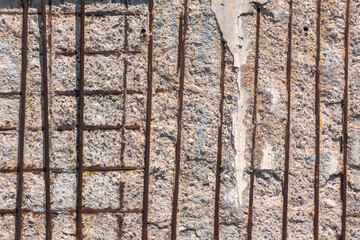 old damaged and weathered concrete wall with rusty iron rods,