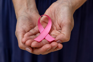 woman holding pink bow in hands. Breast cancer prevention campaign. Pink October