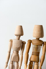 two manikins or mannikins pose with wooden cups on a light background