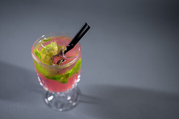 refreshing pink lemonade with mint or rose cocktail in glass on grey background