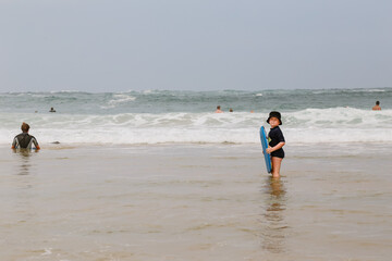 Little blonde boy swimming at the beach with boogie board